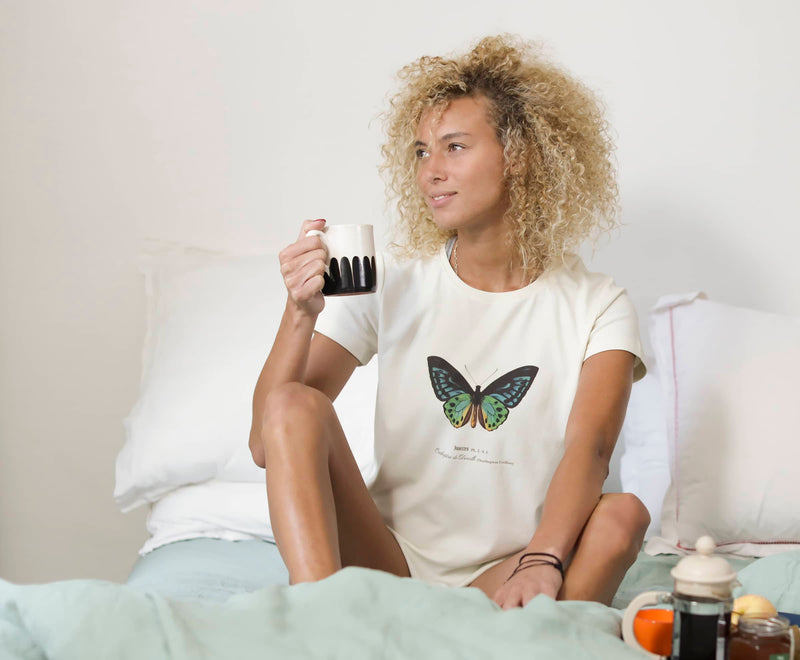 Marjorie prend son petit-déjeuner au lit et porte un T-Shirt Fanatura femme papillon