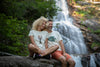 Marjorie et Gilles assis devant la cascade de Runes (48) portant respectivement un T-shirt Fanatura femme homard taille S et un T-shirt Fanatura mixte poisson taille M