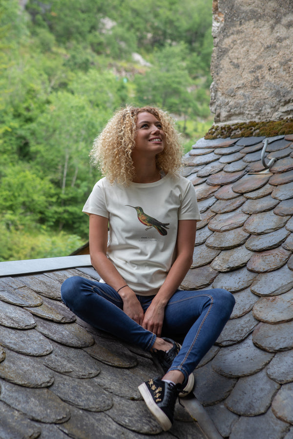 Marjorie assise sur un toit en lauzes de Castelbouc (48) portant un T-shirt Fanatura femme oiseau taille S